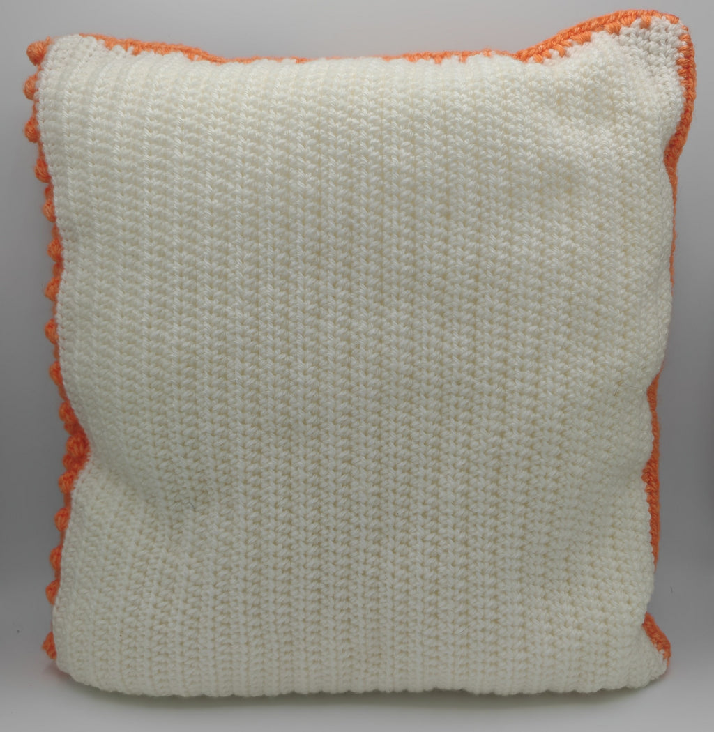 Rückseite eines handgehäkelten Kissens in Cremeweiß mit strukturierter Häkeloptik und orangefarbener Umrandung