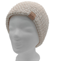 Handgehäkelte Beanie Mütze in Creme mit dezentem Glitzer, getragen auf Schaufensterkopf, Handmade Label sichtbar