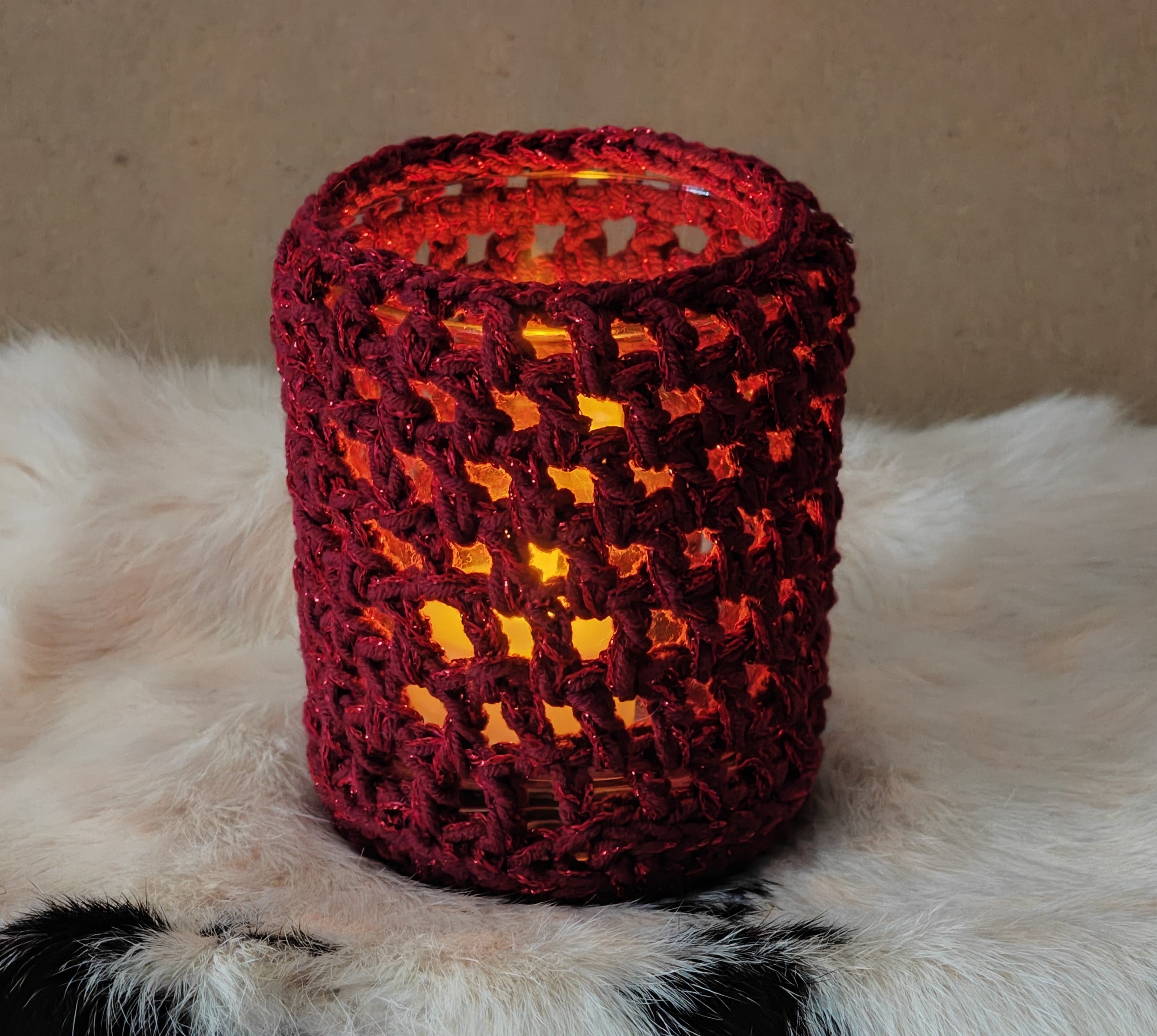 Handgearbeiteter Teelichthalter aus rotem Garn mit warmem Kerzenschein